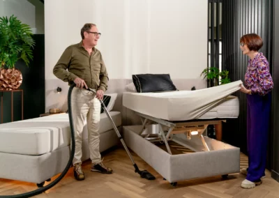 Een senioren echtpaar maakt samen een deelbaar hoog-laag bed op, dat in de hoge stand staat voor meer gemak.