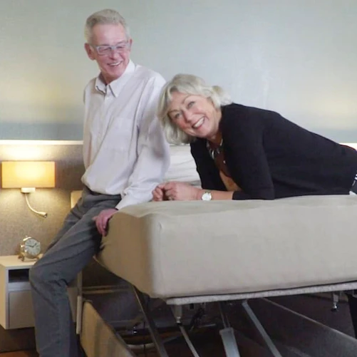 Ouder koppel, waarvan de man Parkinson heeft, op een seniorenbed met hoog-laag functie.
