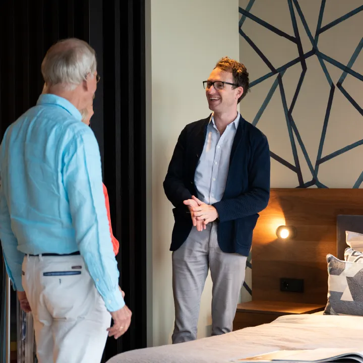 Ontwerper met klanten in de showroom, in gesprek over design bedden